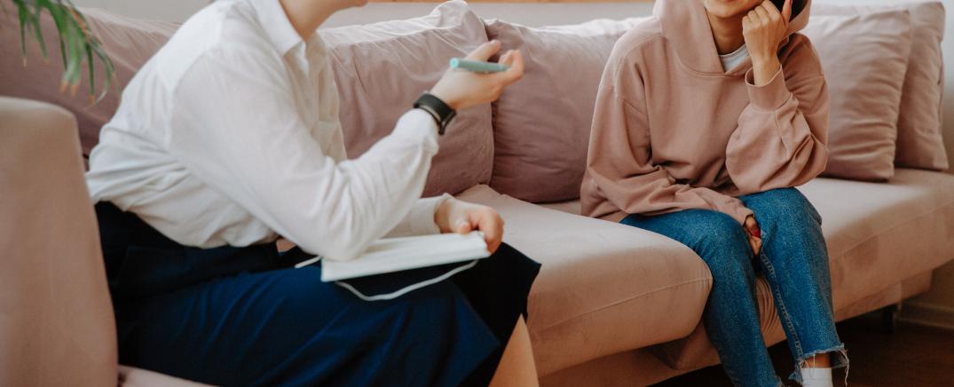 Joven paciente en sesión de terapia individual, escuchando a su terapeuta en un entorno cómodo