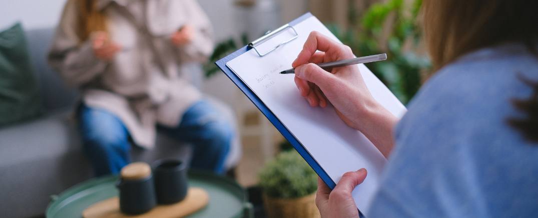 Psicóloga tomando notas durante una sesión con una paciente en tratamiento por patología dual