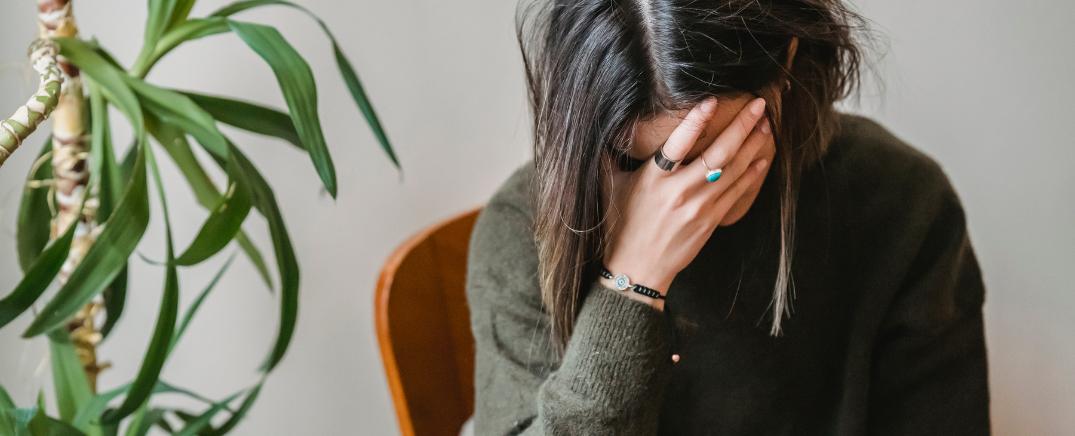 Mujer angustiada sentada con la cabeza entre las manos, reflejando el impacto emocional del craving durante la recuperación de adicciones.