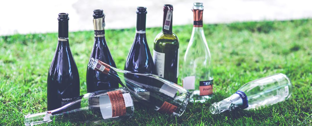 Botellas vacías en el césped después de un botellón, símbolo del Alcohol en la adolescencia en España en 2025