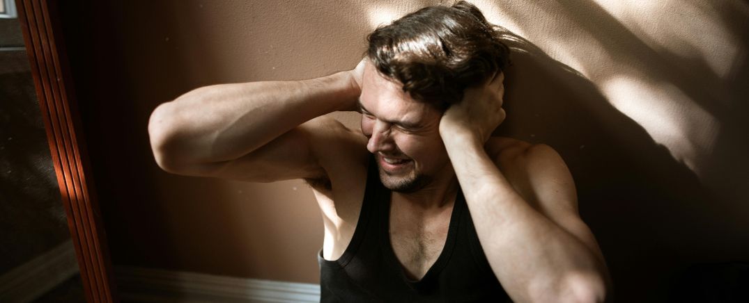 Persona con gesto de angustia y tensión emocional, representando los cambios psicológicos y de comportamiento en el consumo de cocaína.