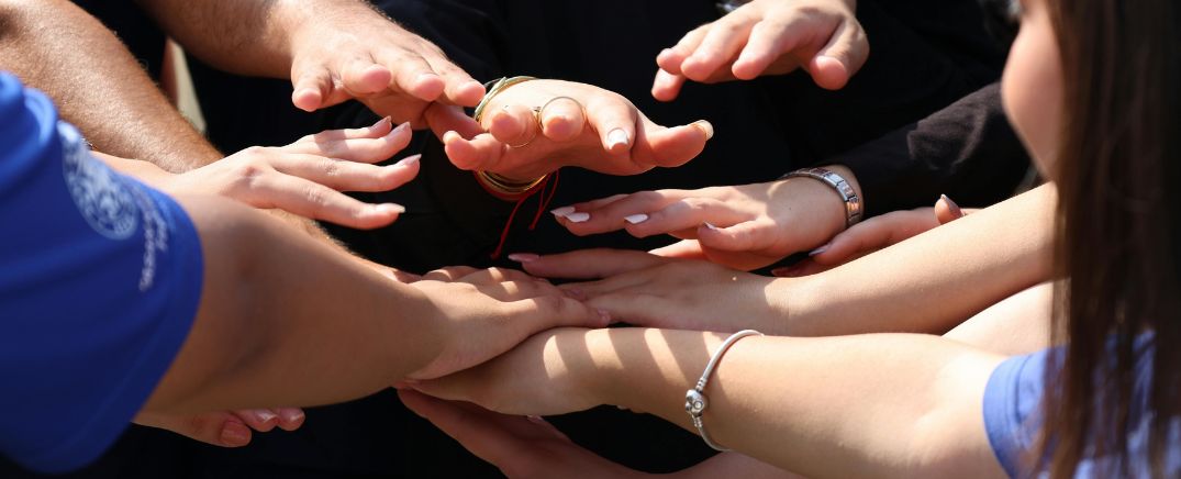 Manos de varias personas unidas en círculo, simbolizando apoyo familiar y acompañamiento durante un proceso de recuperación del alcoholismo.